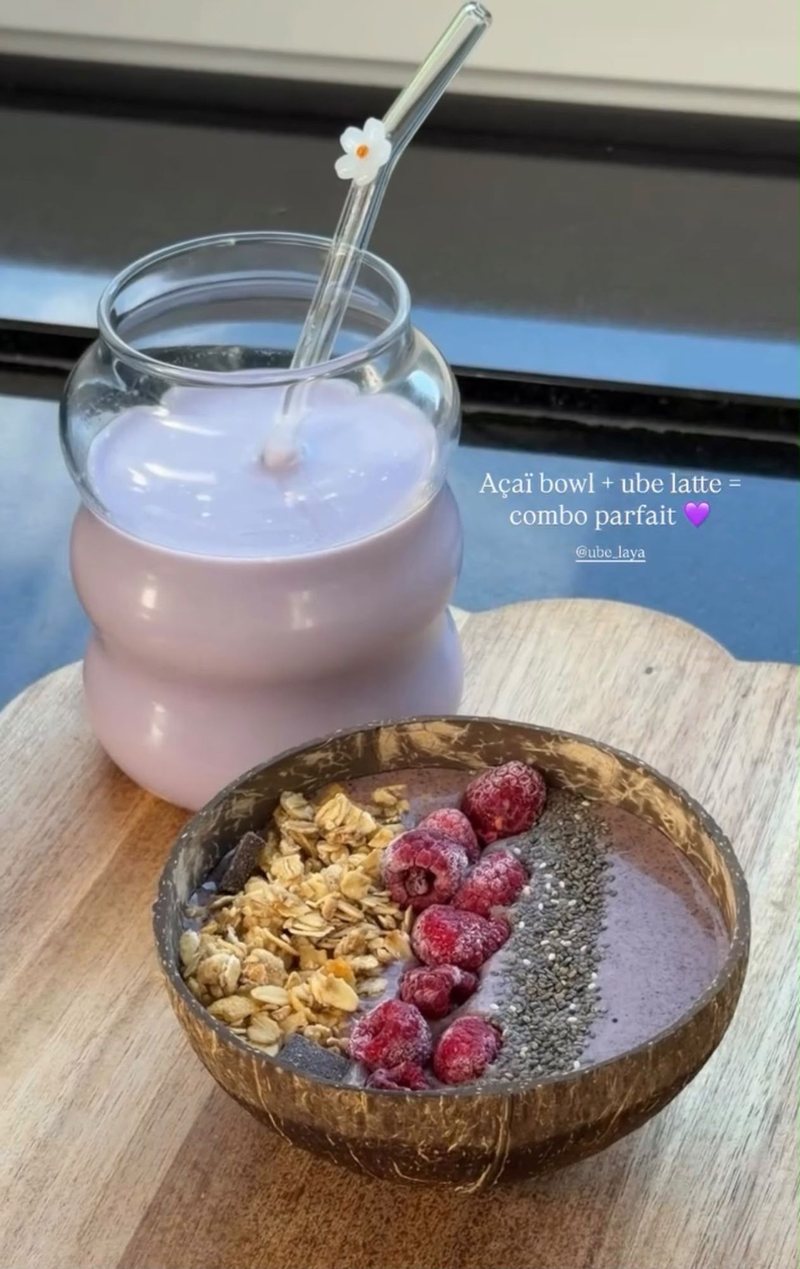 Ube latte with a flower straw and an açaí bowl with raspberries