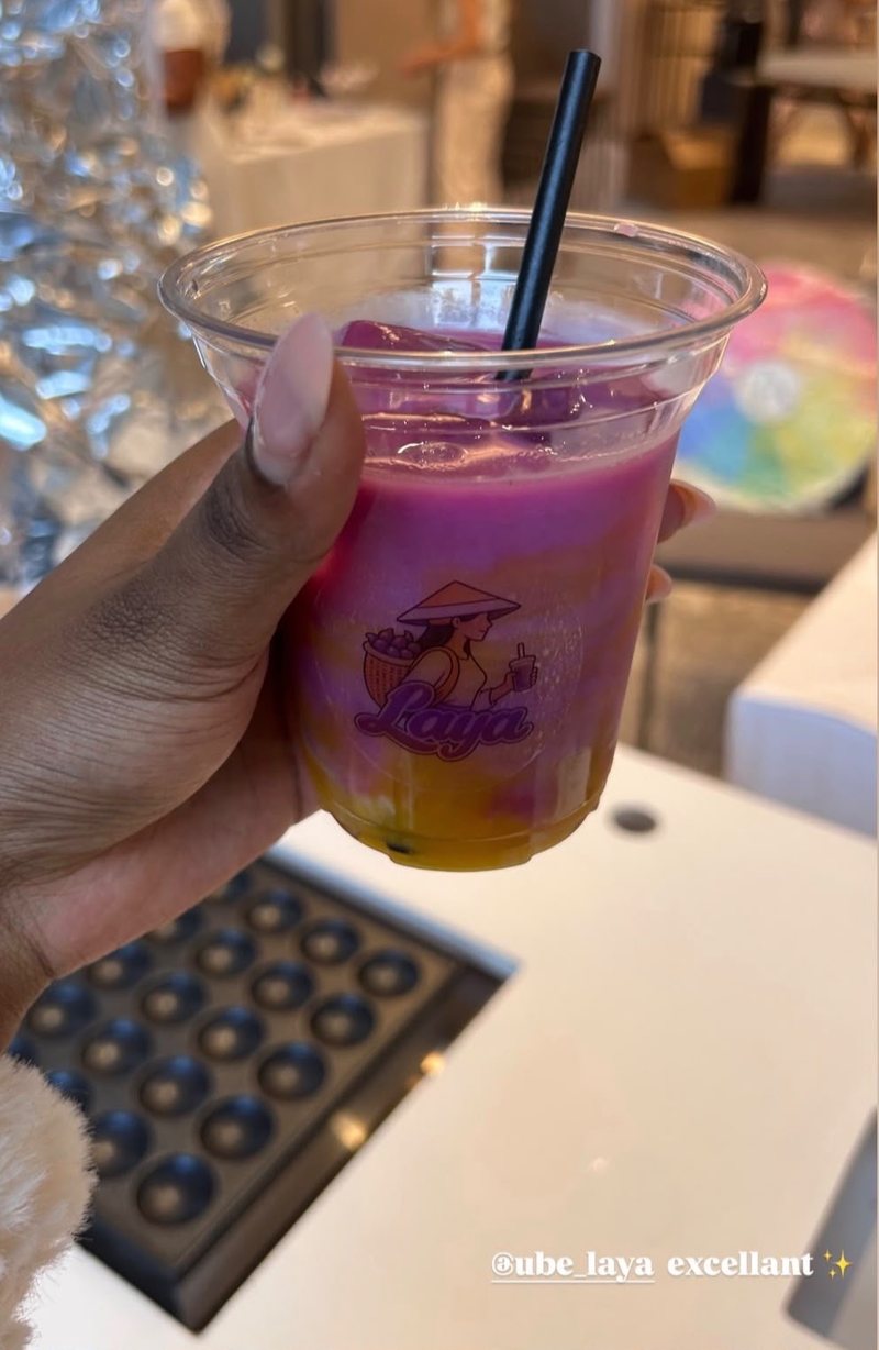Pink iced ube latte with mango in a Laya cup