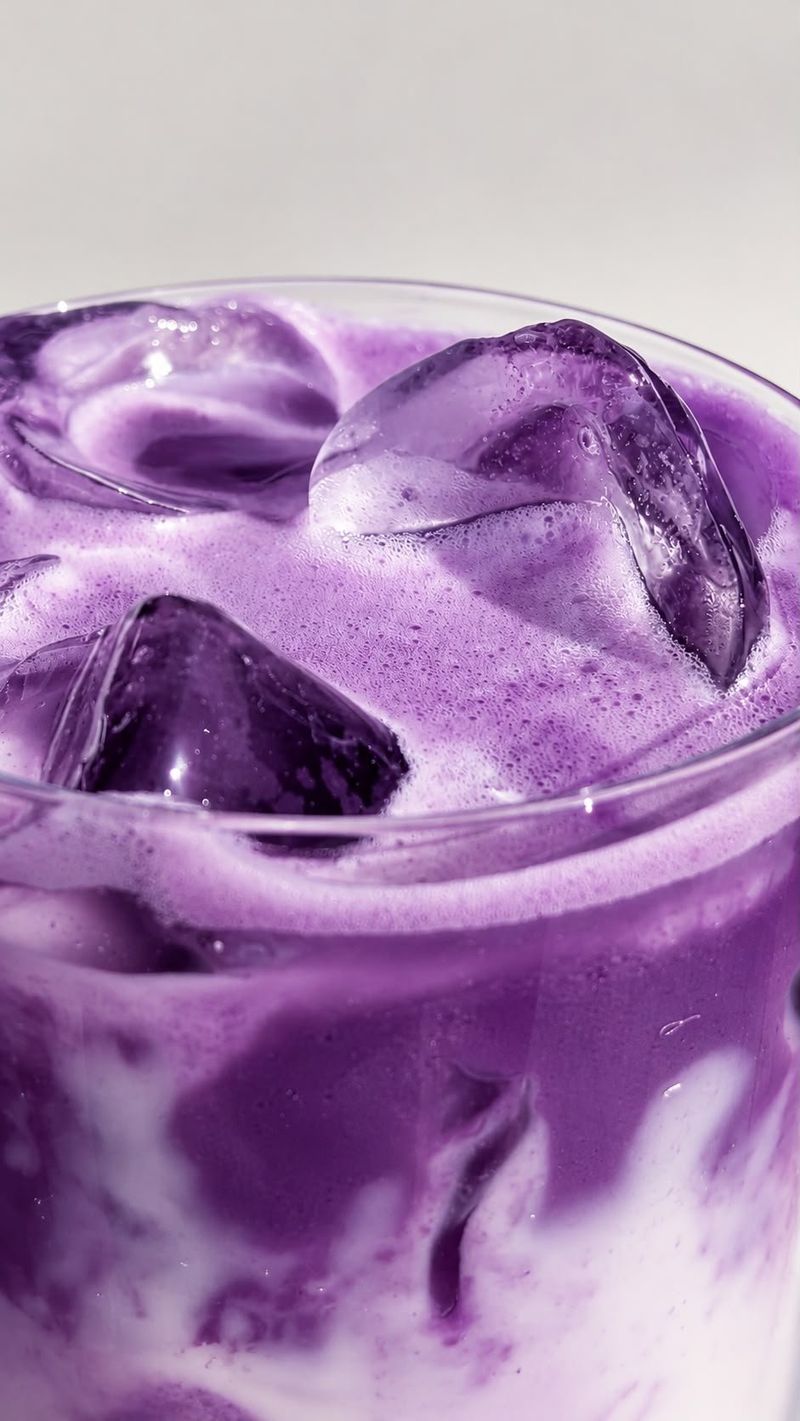 Close-up of a purple and white iced ube latte with ice cubes