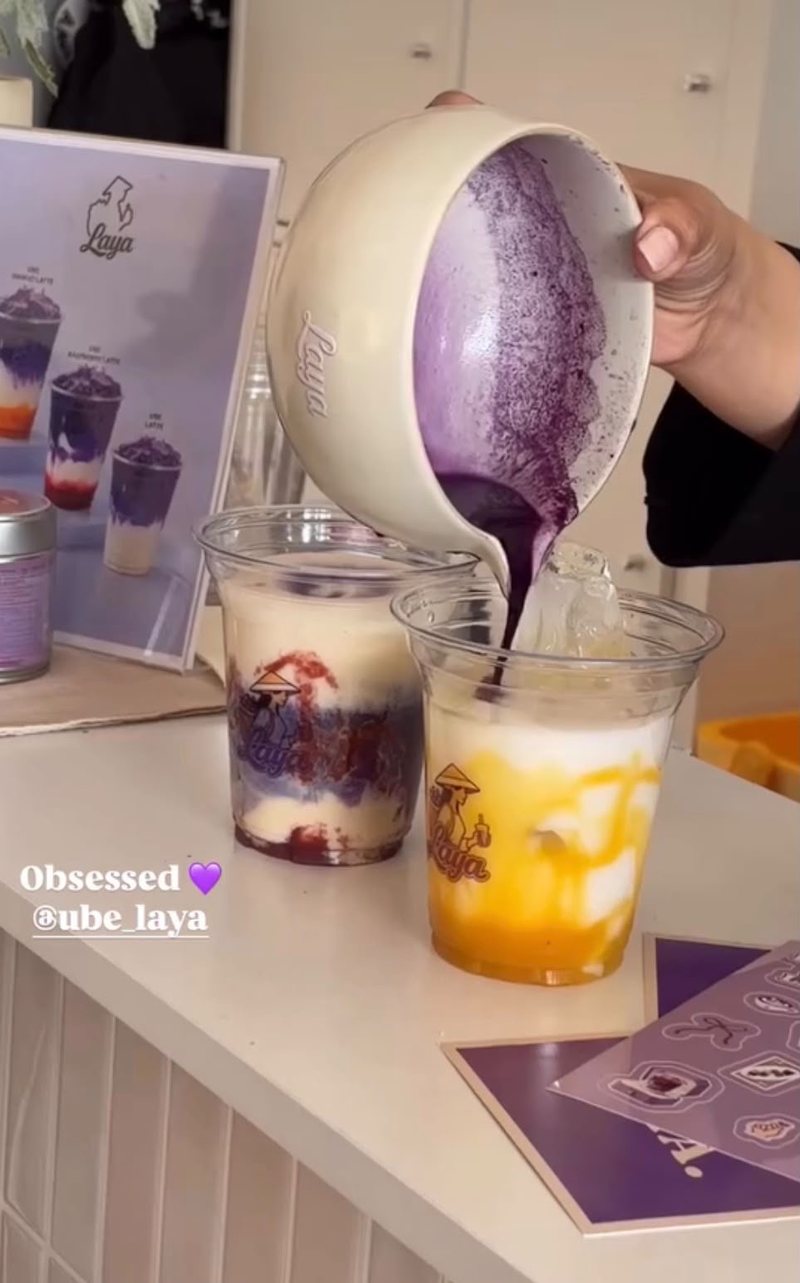 Ube latte poured over a red berry latte in a Laya cup